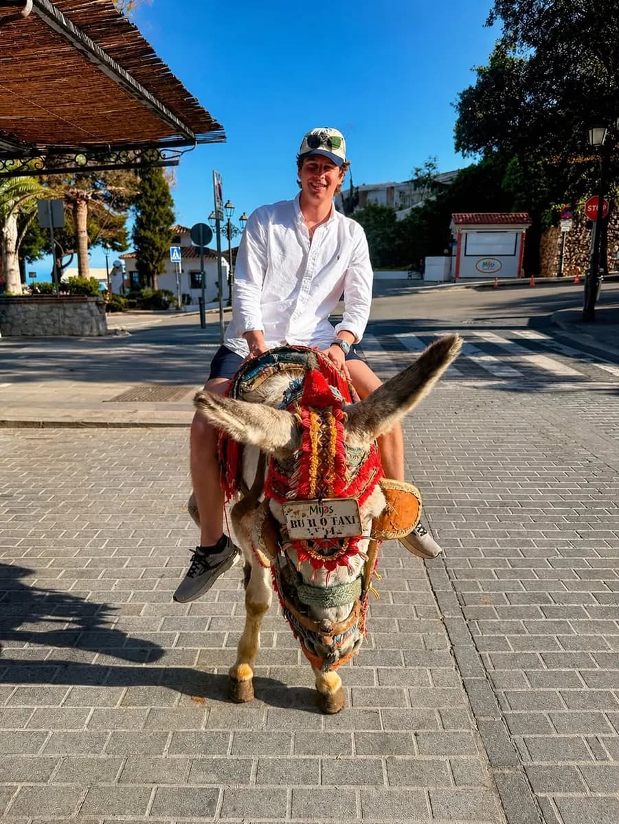 Andy riding a decorated donkey on a street in southern Spain
