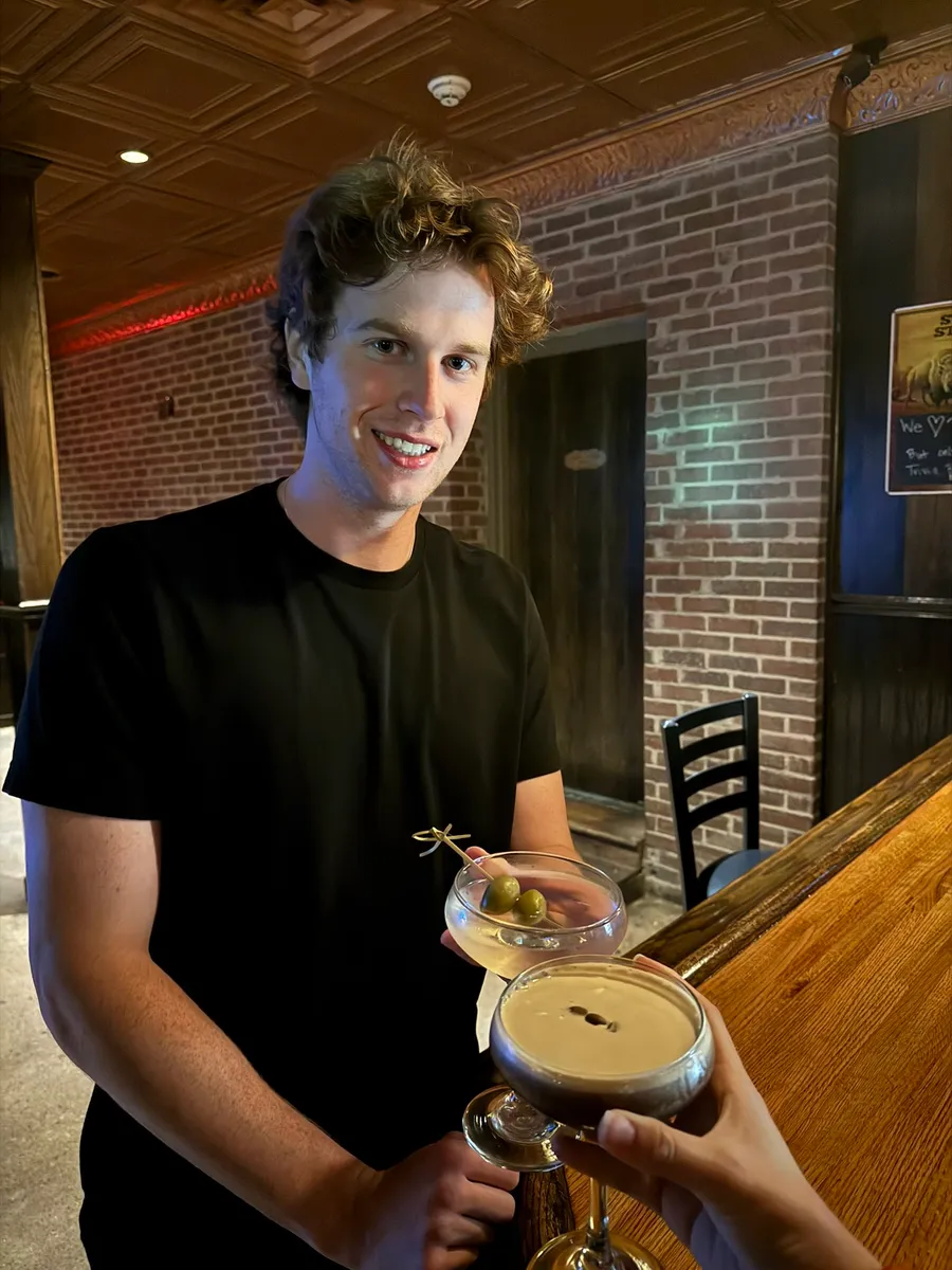 Andy at the bar at O Pub holding two martinis