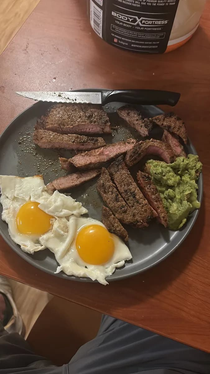 Steak, fried eggs and guacamole on a plate